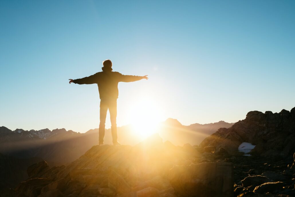 A person standing on a mountain looking at the sunset