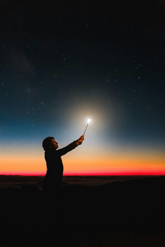 Person standing in the dark holding a light